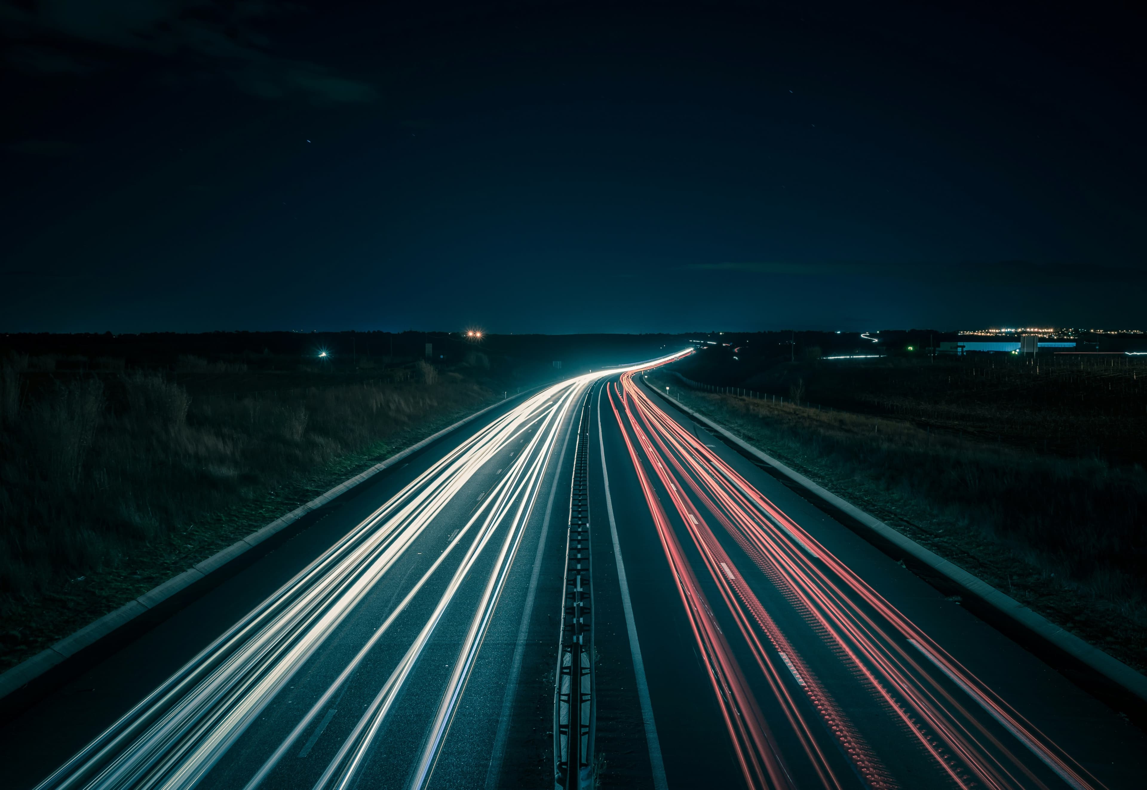A long-exposure night view of highway traffic, representing the scale of a 24/7 transportation network